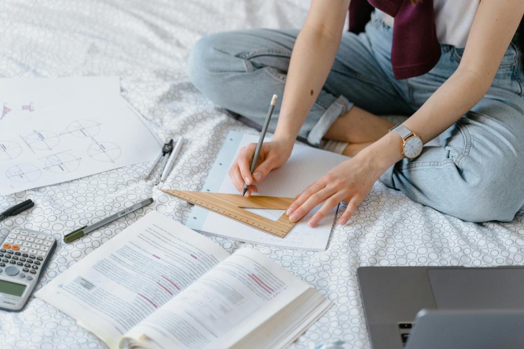 Student sitting cross-legged doing homework using protractor.